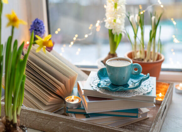 Coffee cup, open book, beautiful flowers, sparkle candles on win