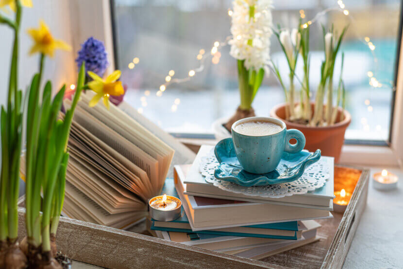 Coffee cup, open book, beautiful flowers, sparkle candles on win