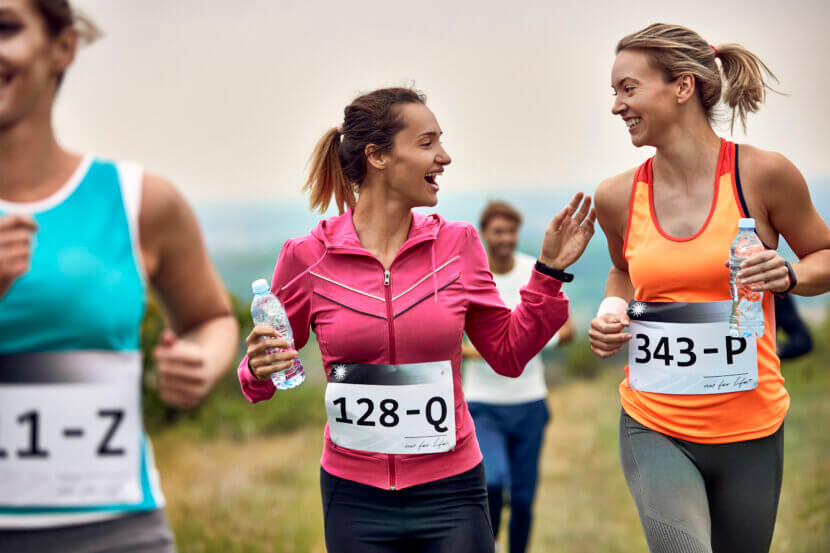 Fit for the women's run: How to prepare optimally Happy female runners communicating while participating in marathon in nature.