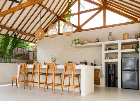 Cuisine minimaliste ouverte, avec des tabourets de bar en bois et des suspensions en rotin, dans une villa tropicale