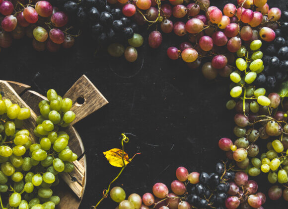 Assortment of fresh grape on cutting board. Grey wooden background.