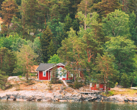 Suède. De magnifiques chalets suédois en rondins rouges sur la côte rocheuse de l'île en été. Paysage de lac ou de rivière