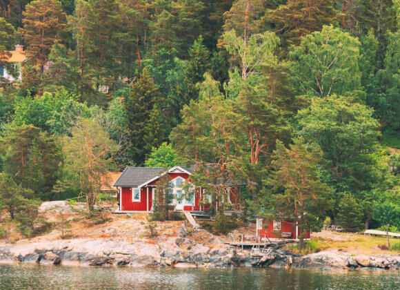 Suède. De magnifiques chalets suédois en rondins rouges sur la côte rocheuse de l'île en été. Paysage de lac ou de rivière